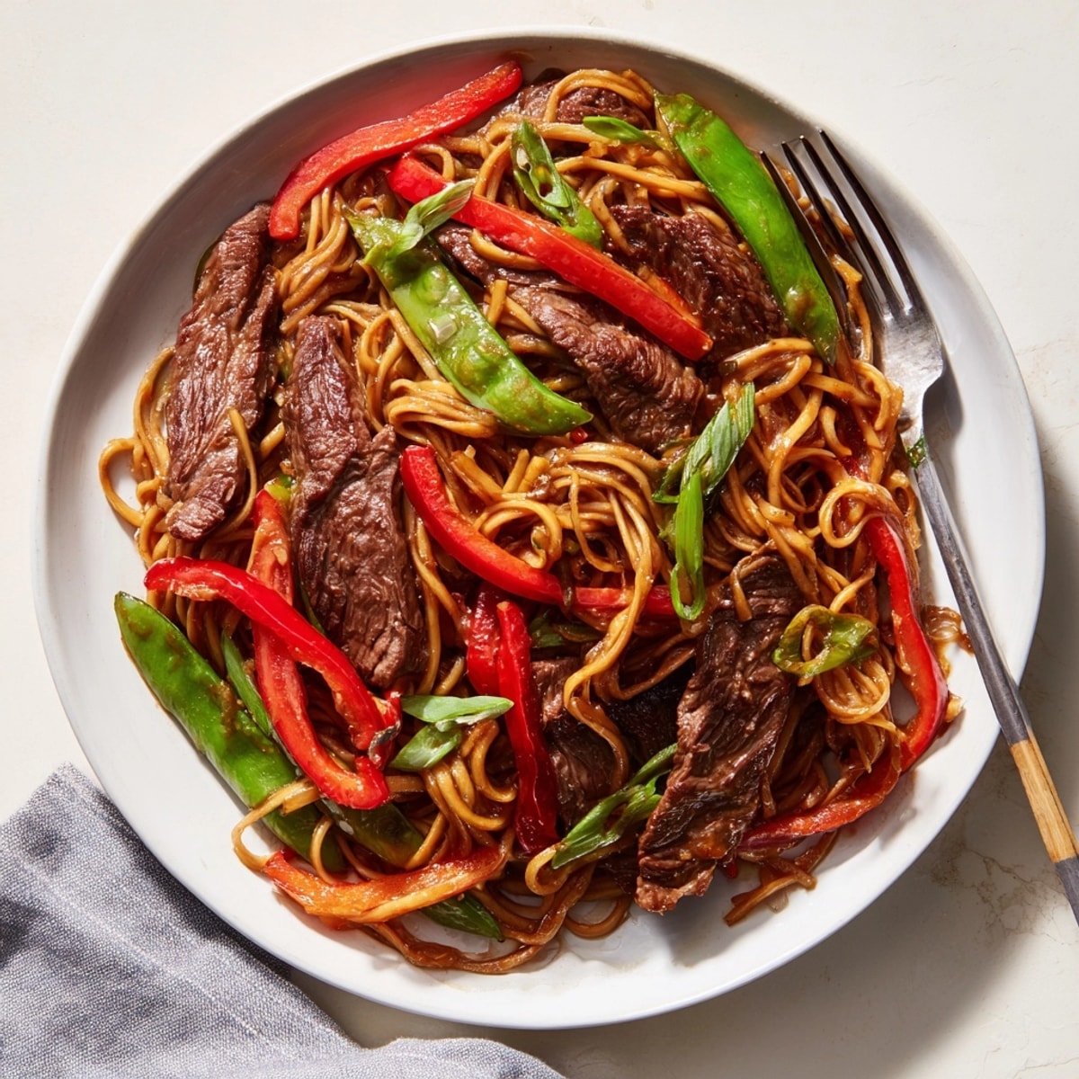 Top-down view of steamy Mongolian Beef Noodles, garnished with scallions, ready to serve.