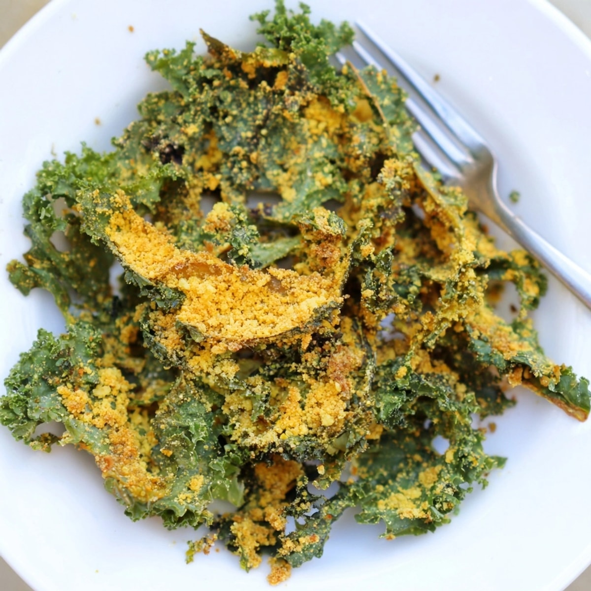 Crispy cheesy kale chips, golden-brown and seasoned, piled on a baking sheet, ready to devour.