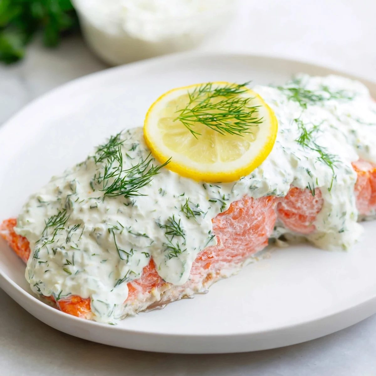 Close-up of perfectly cooked baked salmon, topped with creamy lemon dill sauce, ready to eat.