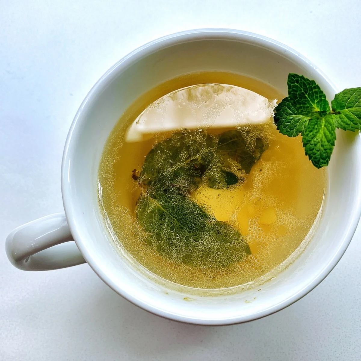 Two steaming cups of Peppermint Tea with Honey sit beside fresh mint sprigs and a honey dipper, creating a cozy, herbal vibe.