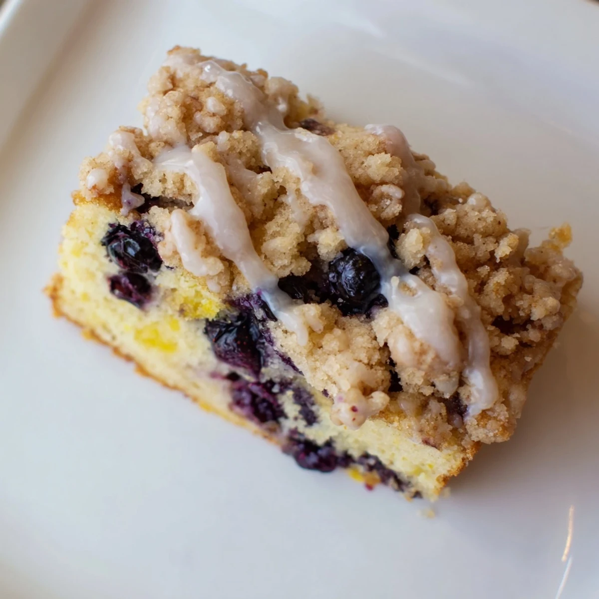 A rustic pan of homemade Lemon Blueberry Coffee Cake drizzled with sweet lemon glaze. 