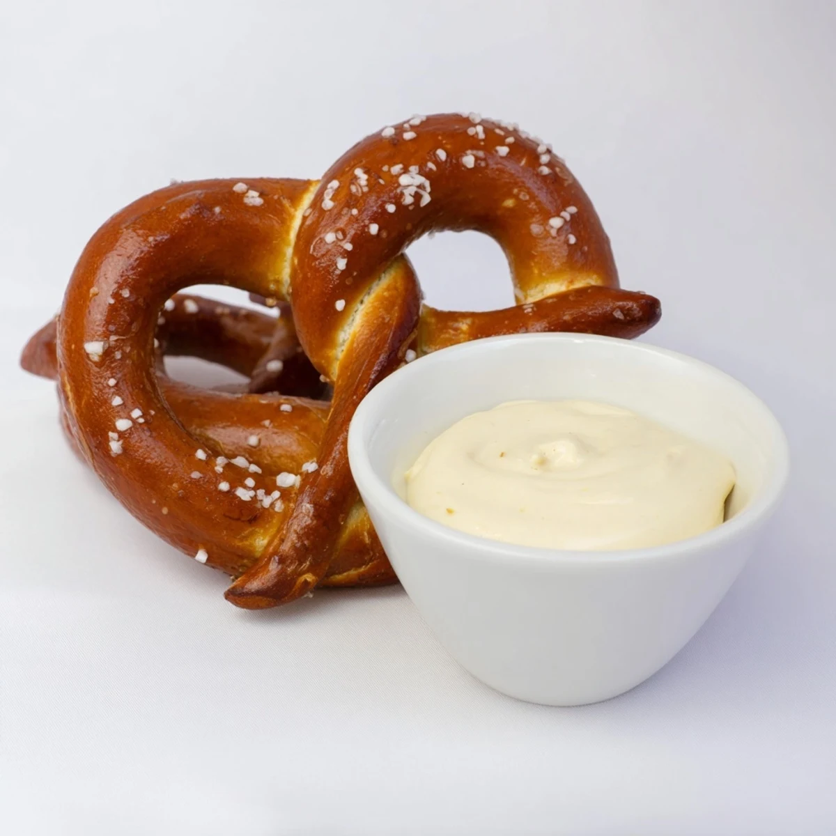 Eight golden Game Day Soft Pretzels with Cheese Sauce are paired with a creamy, tangy dip for snacking.