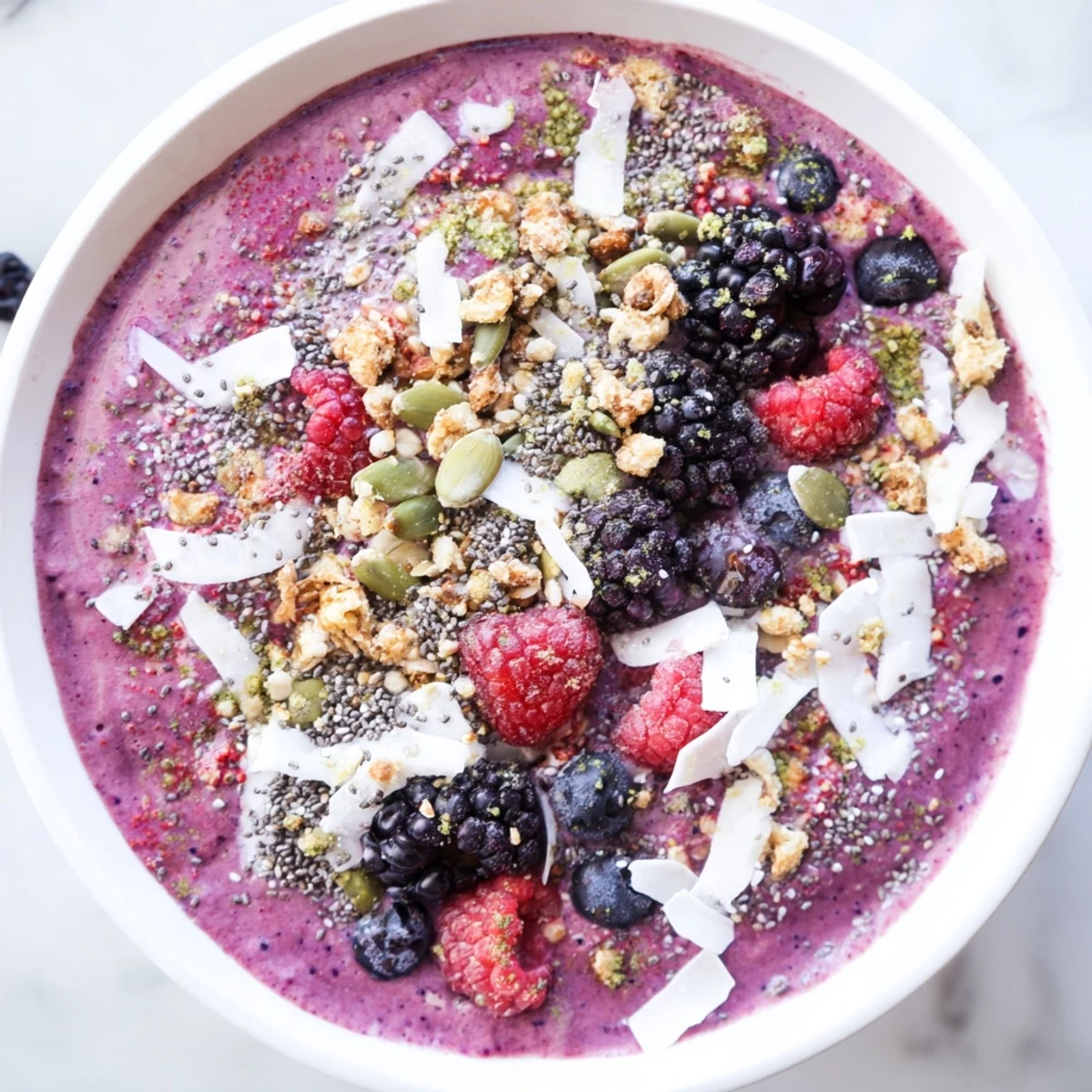 Vibrant Winter Berry Smoothie Bowl in a white bowl with almond milk base and nutritious seed toppings.  