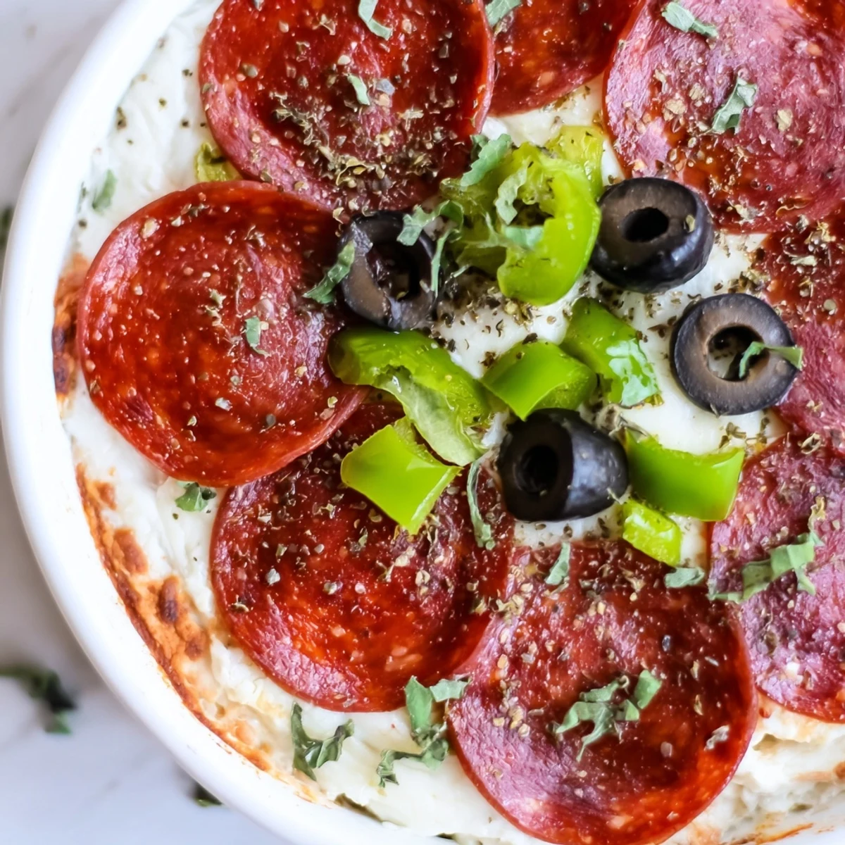A close-up of baked Pepperoni Pizza Dip with beef pepperoni, melted mozzarella and Parmesan, and a zesty pizza sauce base.