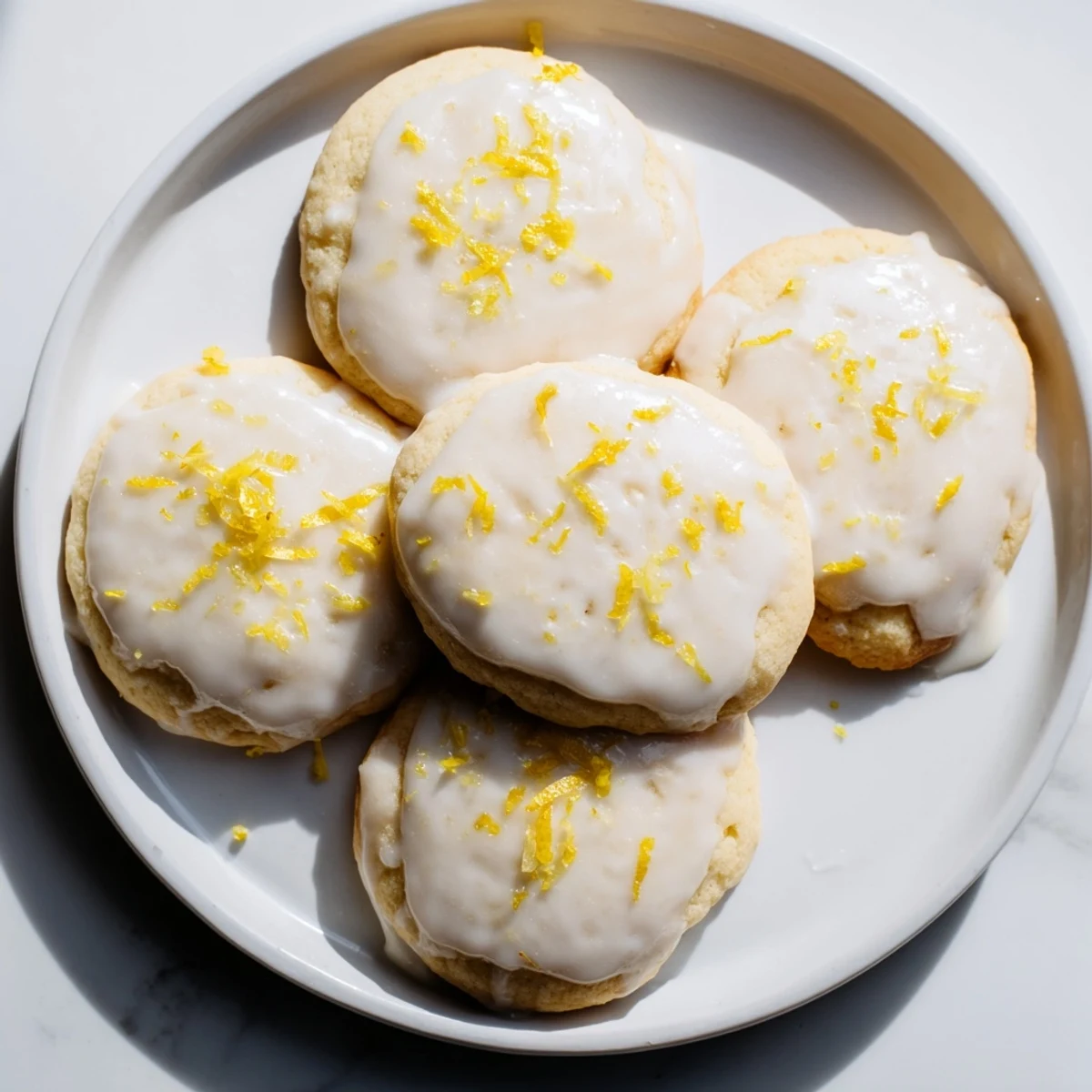 Golden Lemon Ricotta Cookies with Glaze are drizzled with white icing on a cooling rack, showcasing their soft, cake-like texture.