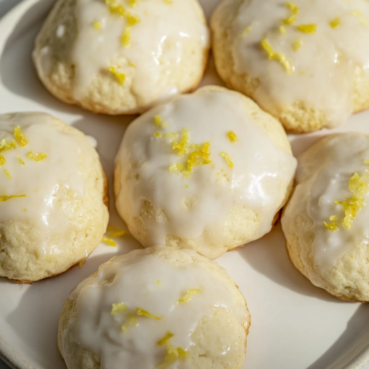 A close-up of Lemon Ricotta Cookies with Glaze reveals a thick, tangy glaze dripping down the sides of the moist, lemony cookie.