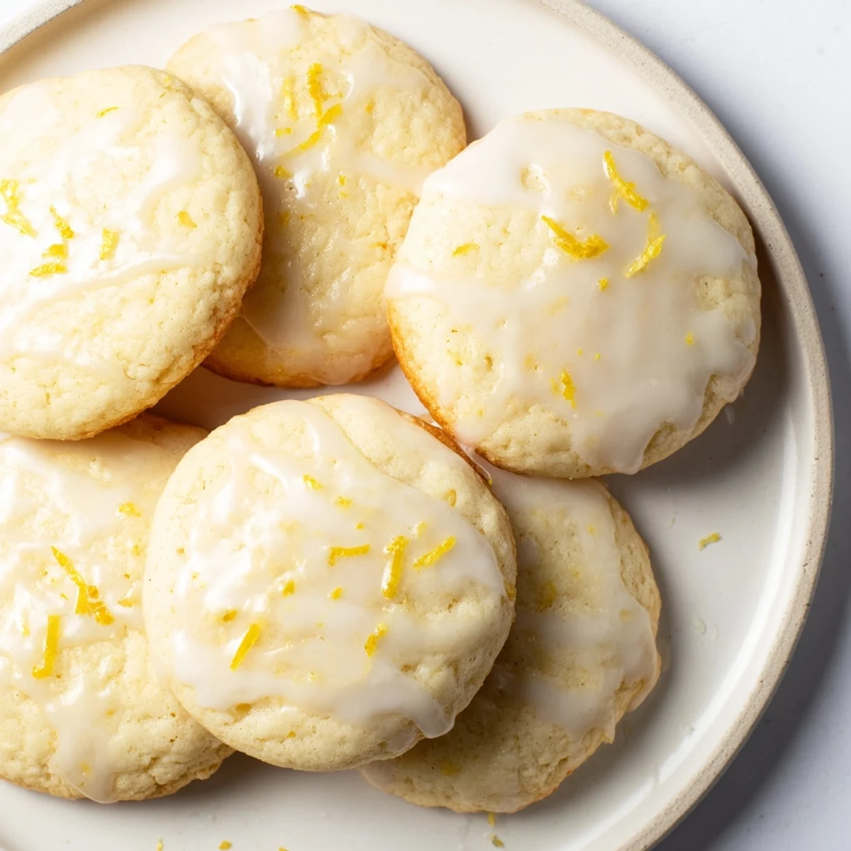 Overhead view of Lemon Ricotta Cookies with Glaze arranged on a platter with fresh lemon slices, perfect for a sweet dessert snack.