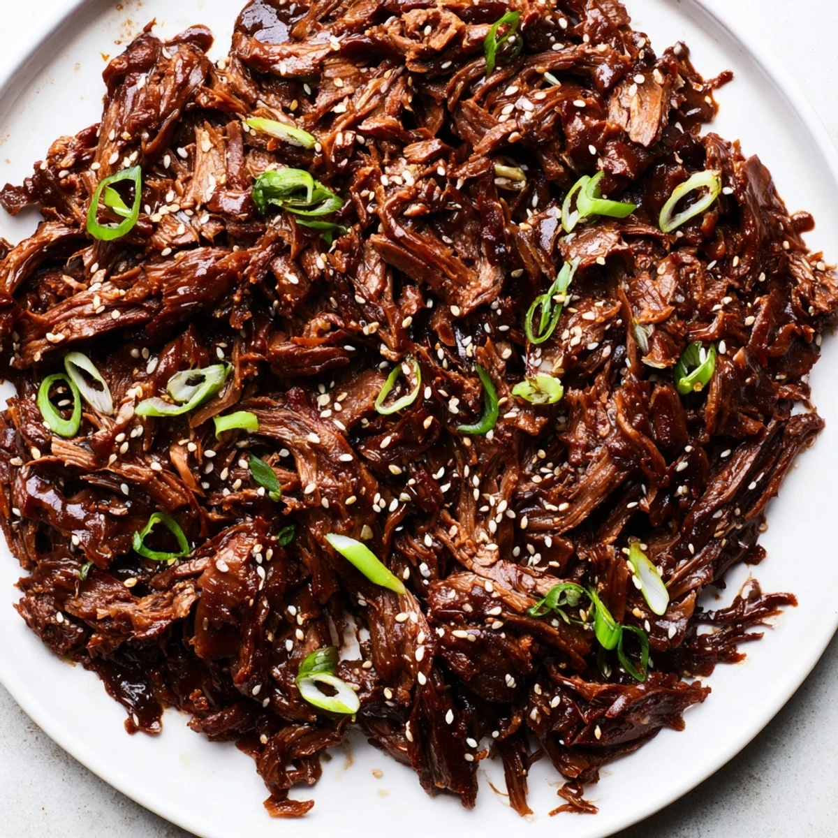 Slow cooker Korean beef simmering in a savory-sweet sauce, garnished with green onions and sesame seeds over steamed rice.