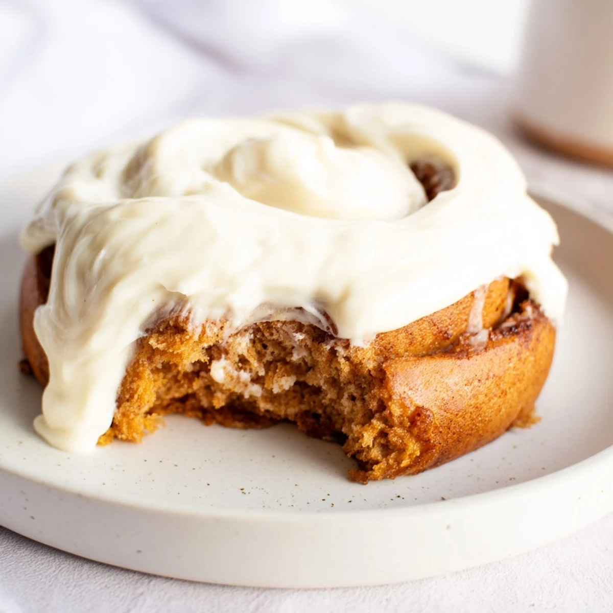Freshly baked Keto Cinnamon Buns with gooey cinnamon swirls and cream cheese icing on a rustic plate.  
