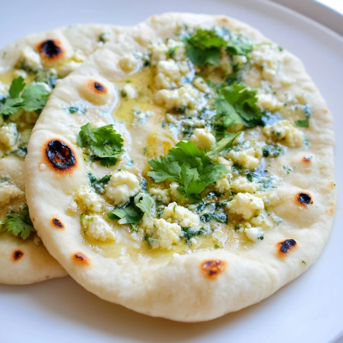 Freshly cooked Cottage Cheese Garlic Naan brushed with herb butter, showcasing golden spots on a warm skillet, ready to serve with curry.