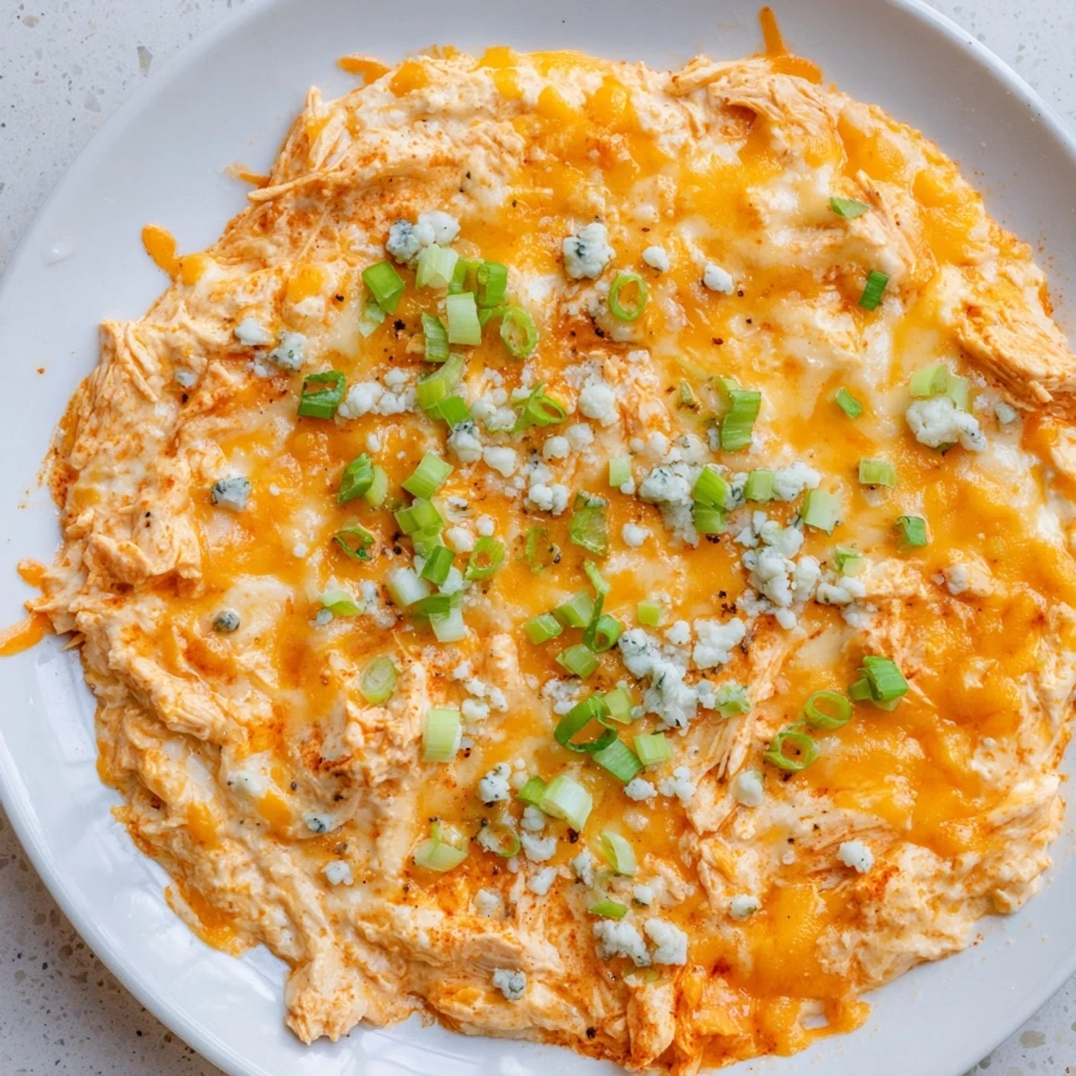 Spicy Keto Buffalo Chicken Dip served with crisp celery sticks and cucumber slices, perfect for a low-carb appetizer spread on a wooden board.