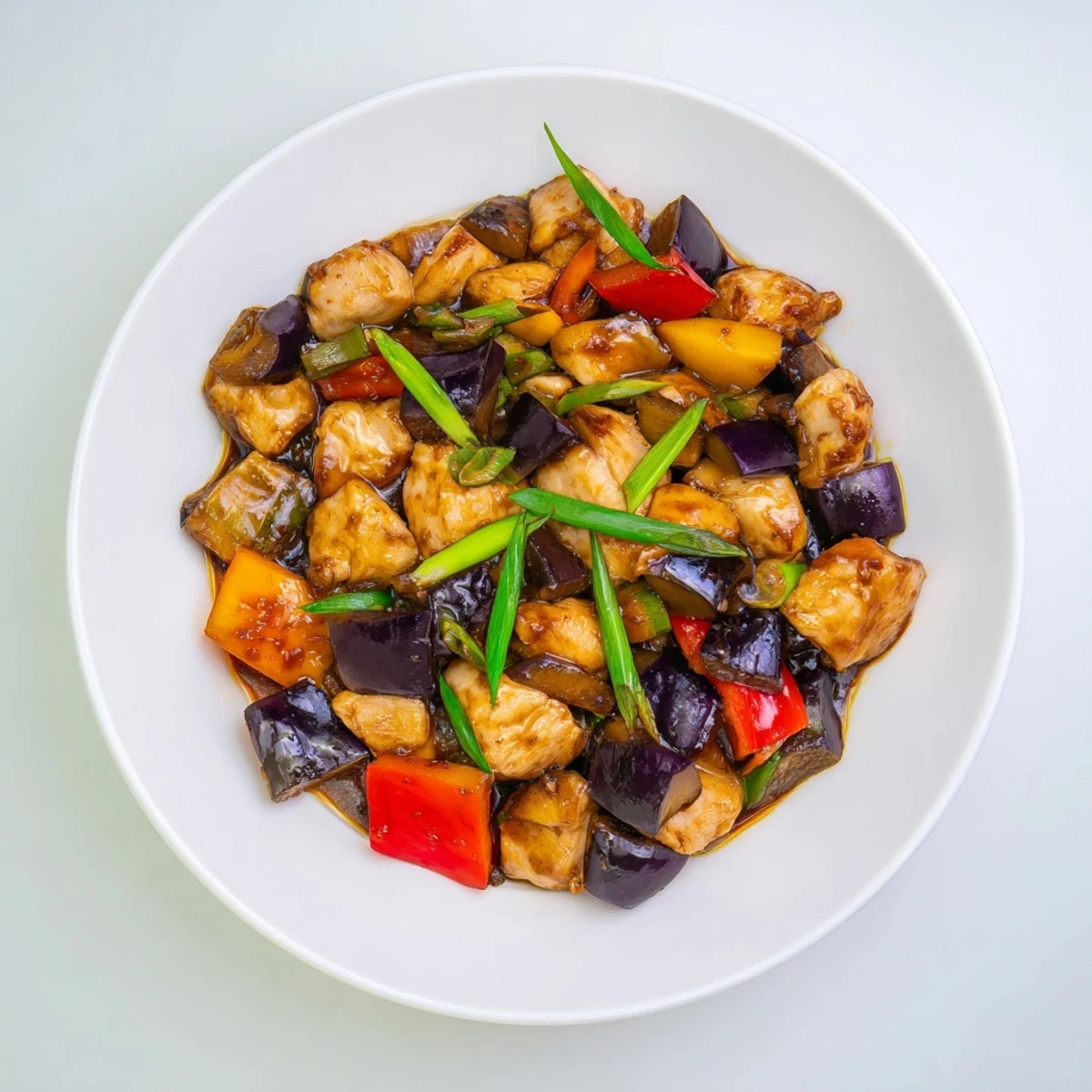 A close-up of vibrant stir-fried Black Vinegar Chicken With Bell Peppers And Eggplant, served hot with steamed jasmine rice. 