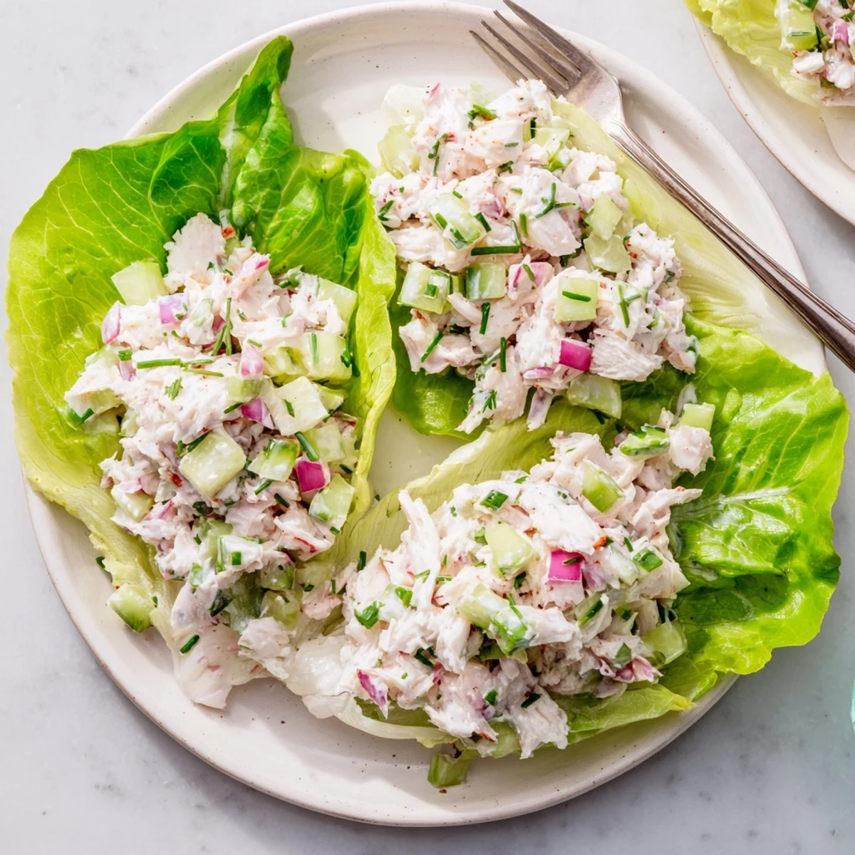 Bright, close-up view of chilled lump crab salad with creamy dressing, diced celery, cucumber, and fresh herbs in a white serving bowl.