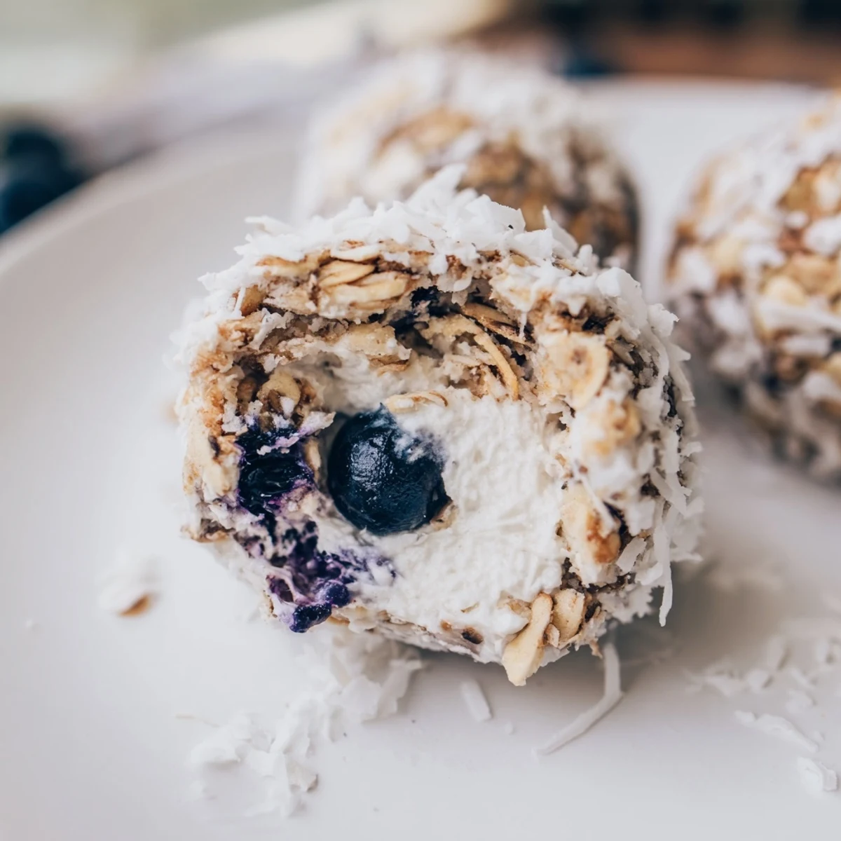 Lemon Blueberry Cottage Cheese Protein Bites on a wooden board, showing soft textures and a light coconut coating.