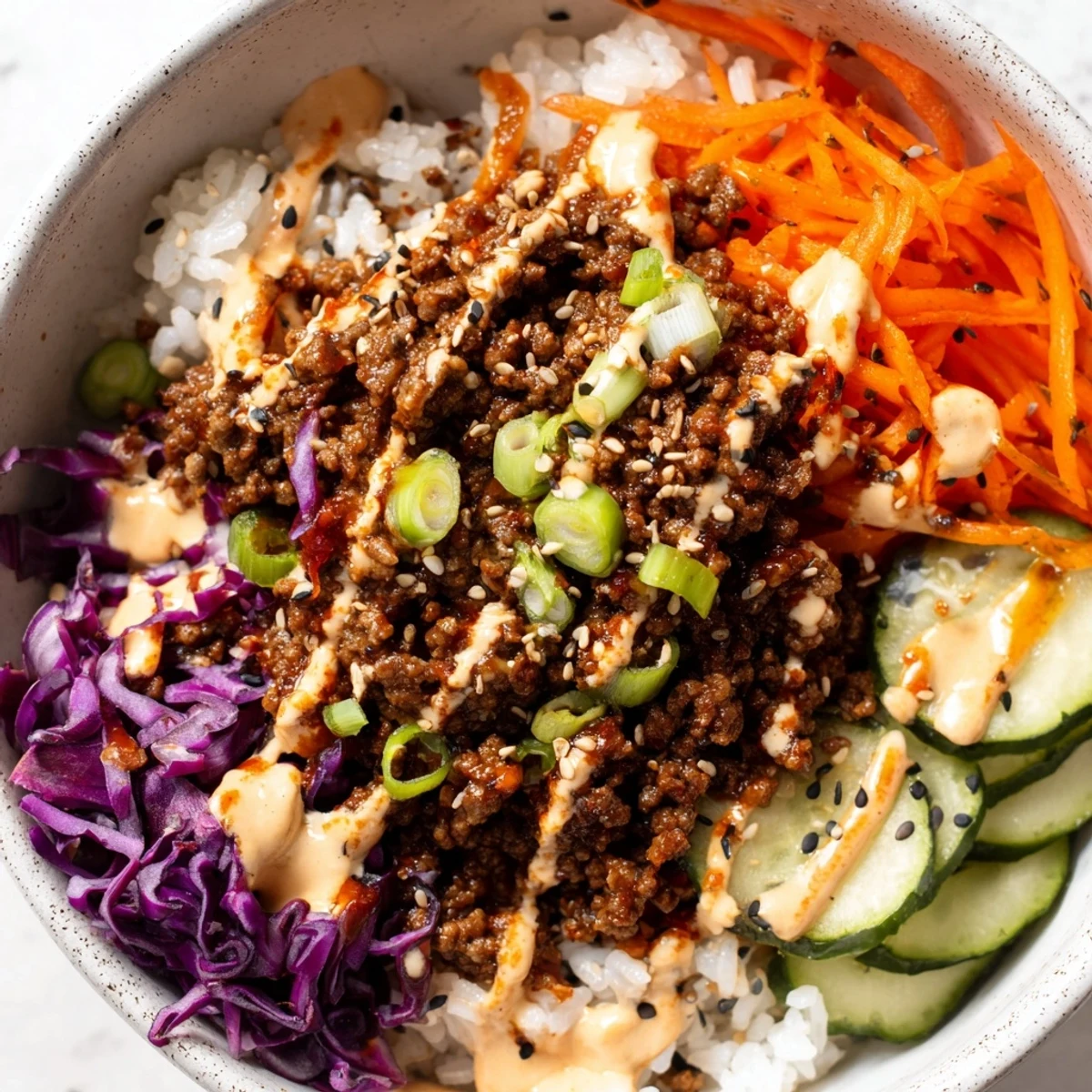Delicious Korean Beef Bowl with Spicy Mayo in a white bowl, garnished with sesame seeds and green onions for extra crunch.