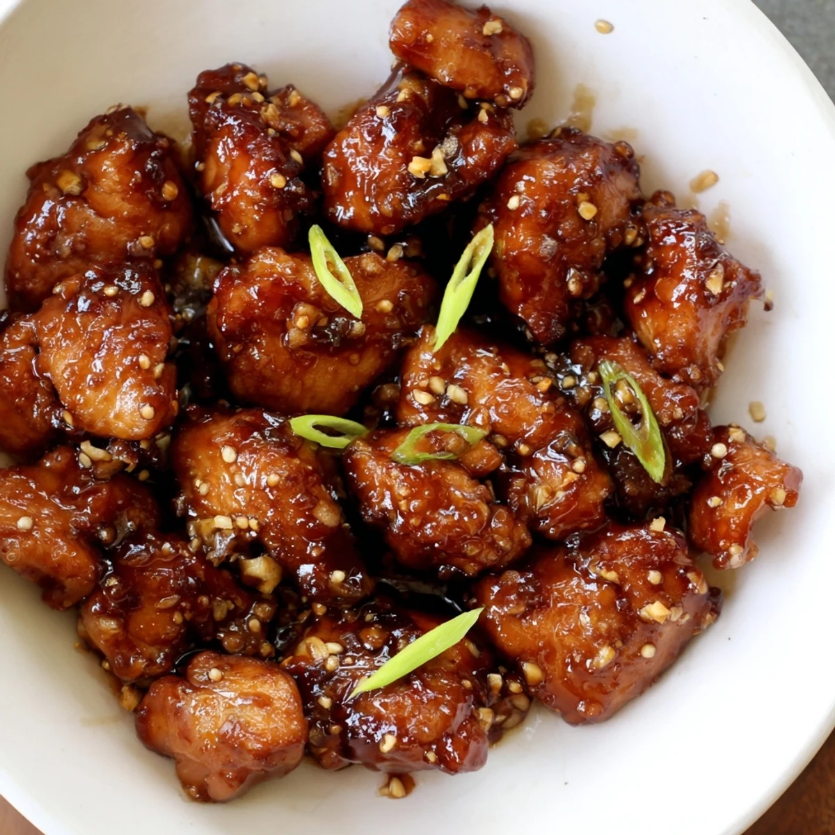 Golden brown Mongolian chicken pieces glazed in a glossy sweet and savory sauce with green onion garnish