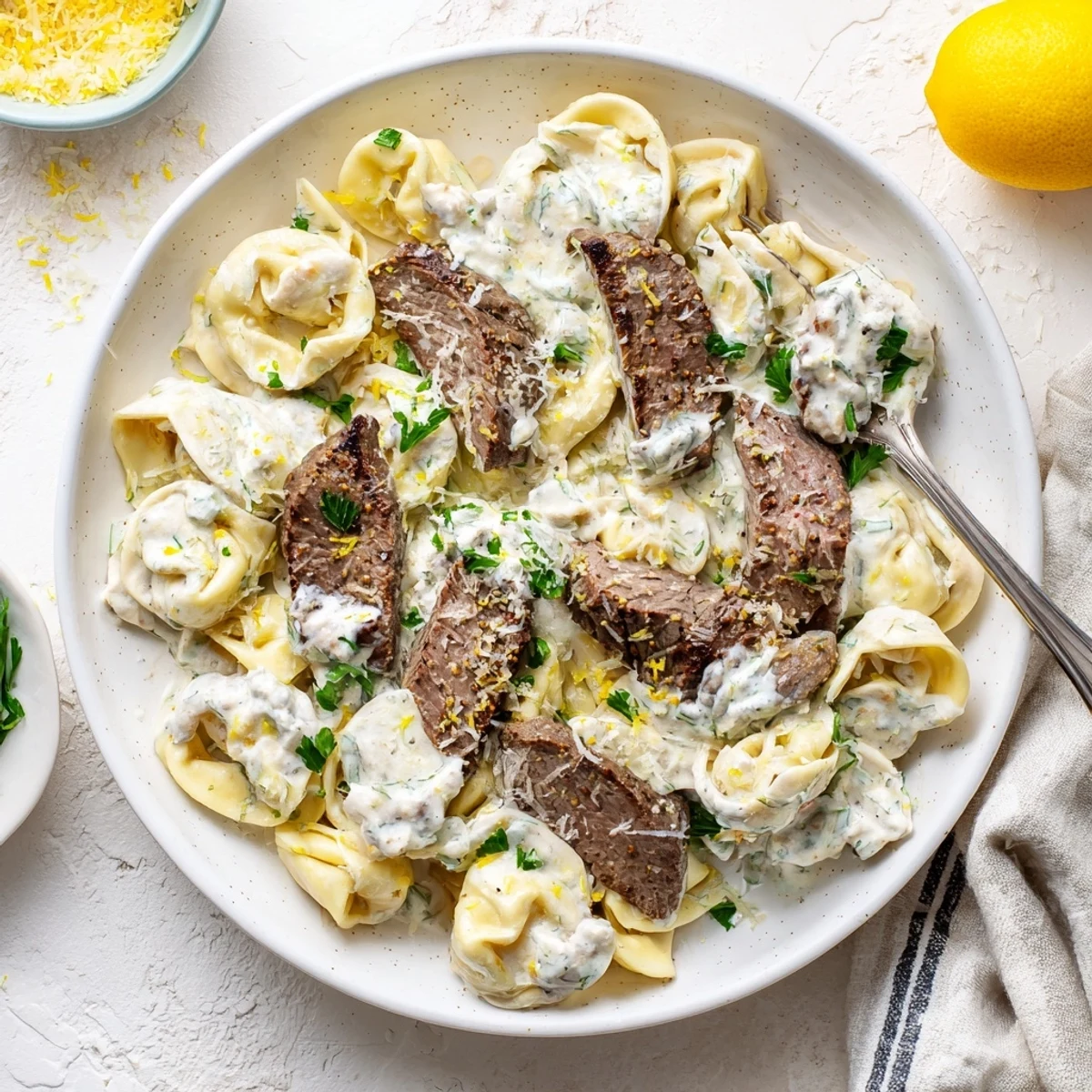 Golden cheese tortellini and sliced steak coated in rich cracked garlic cream sauce with parsley garnish