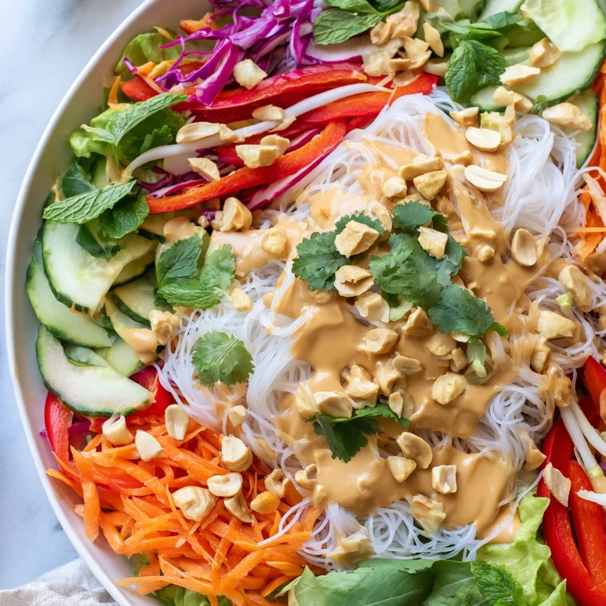 Vibrant Vietnamese-inspired spring roll salad with peanut dressing showcasing colorful julienned vegetables, vermicelli noodles, and chopped peanuts