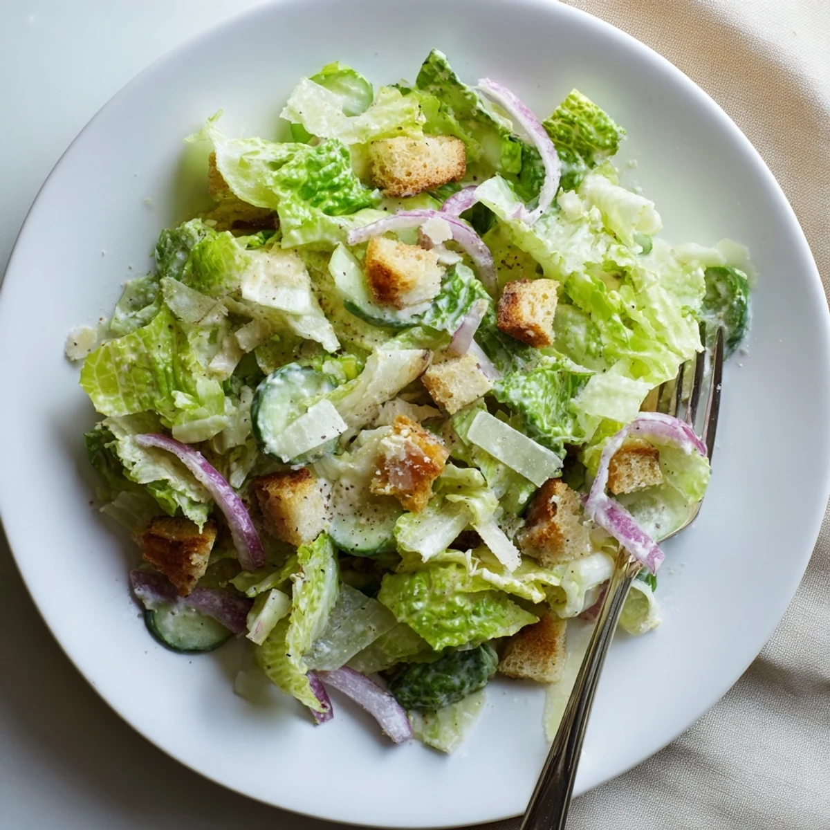 Fresh cucumber Caesar salad featuring crisp cucumbers, crunchy croutons, and creamy white Caesar dressing in a serving bowl