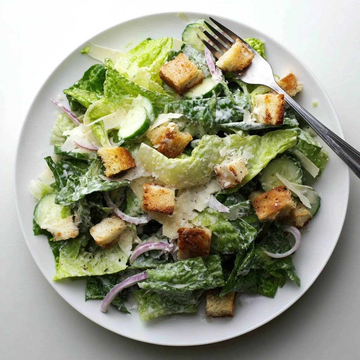 Light cucumber Caesar salad bowl showcasing sliced cucumbers, crisp lettuce, savory croutons, and rich Parmesan garnish