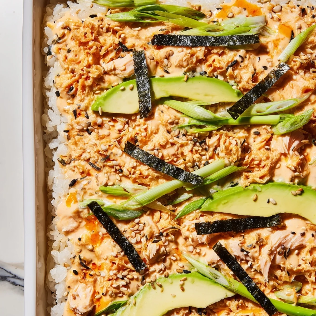 Golden salmon sushi bake topped with creamy sriracha mayo avocado and furikake seasoning