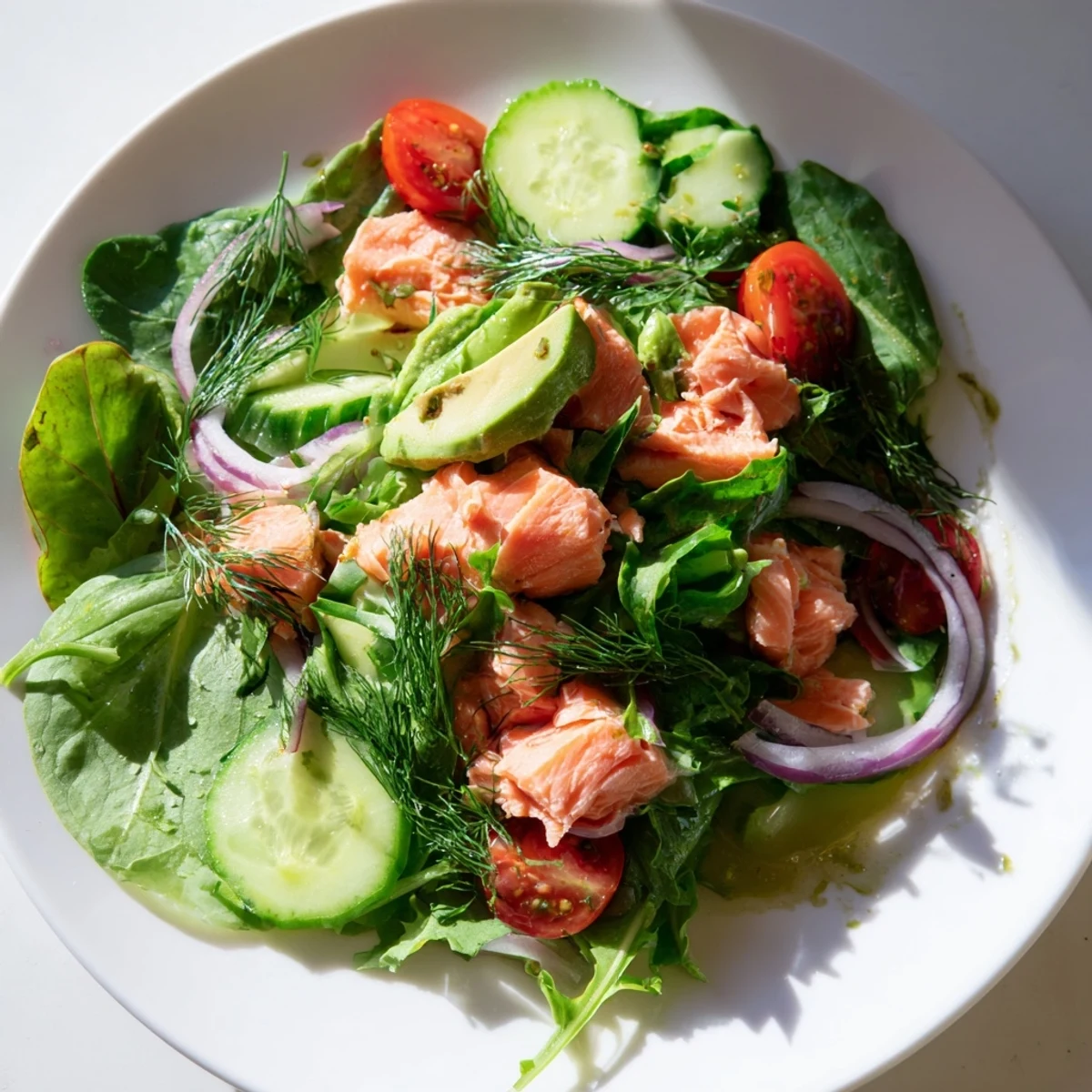Healthy minute salmon salad with tender fish, juicy tomatoes, crisp cucumber, and fresh dill garnish on a bed of greens.