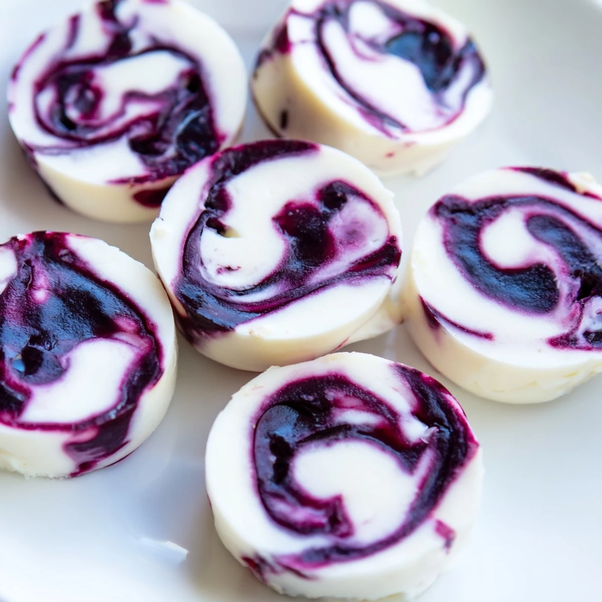 Close-up of blueberry swirl yogurt bites revealing thick ribbons of sweet blueberry compote swirled into chilled white Greek yogurt circles
