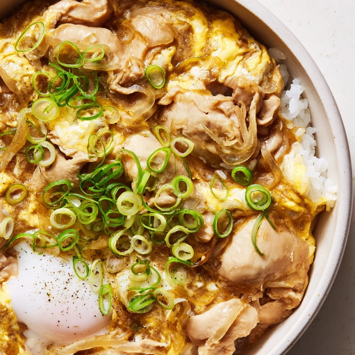 Golden Oyakodon served in a donburi bowl with garnish of fresh green onions