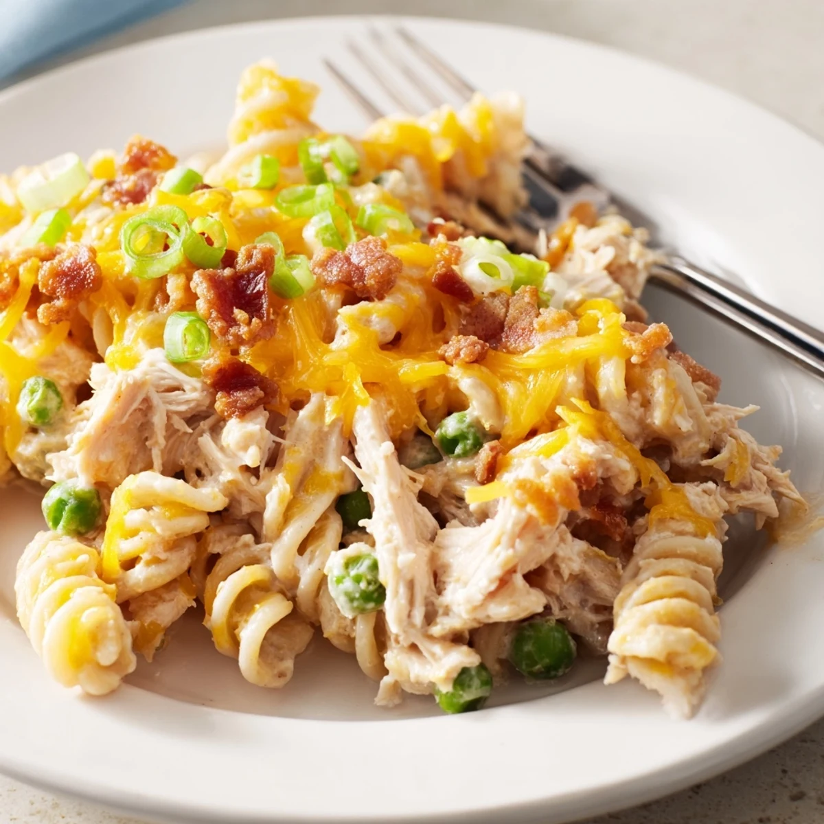 Serving of Crack Chicken Casserole garnished with green onions and bubbling golden cheese