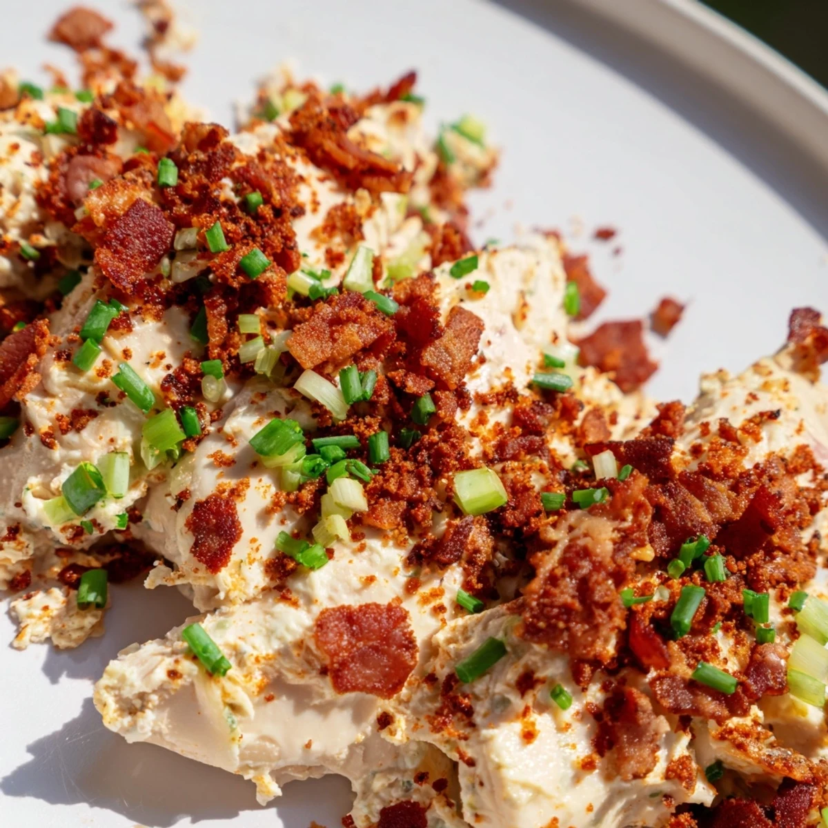 Tender Crockpot Million Dollar Chicken dish garnished with fresh herbs and crispy bacon