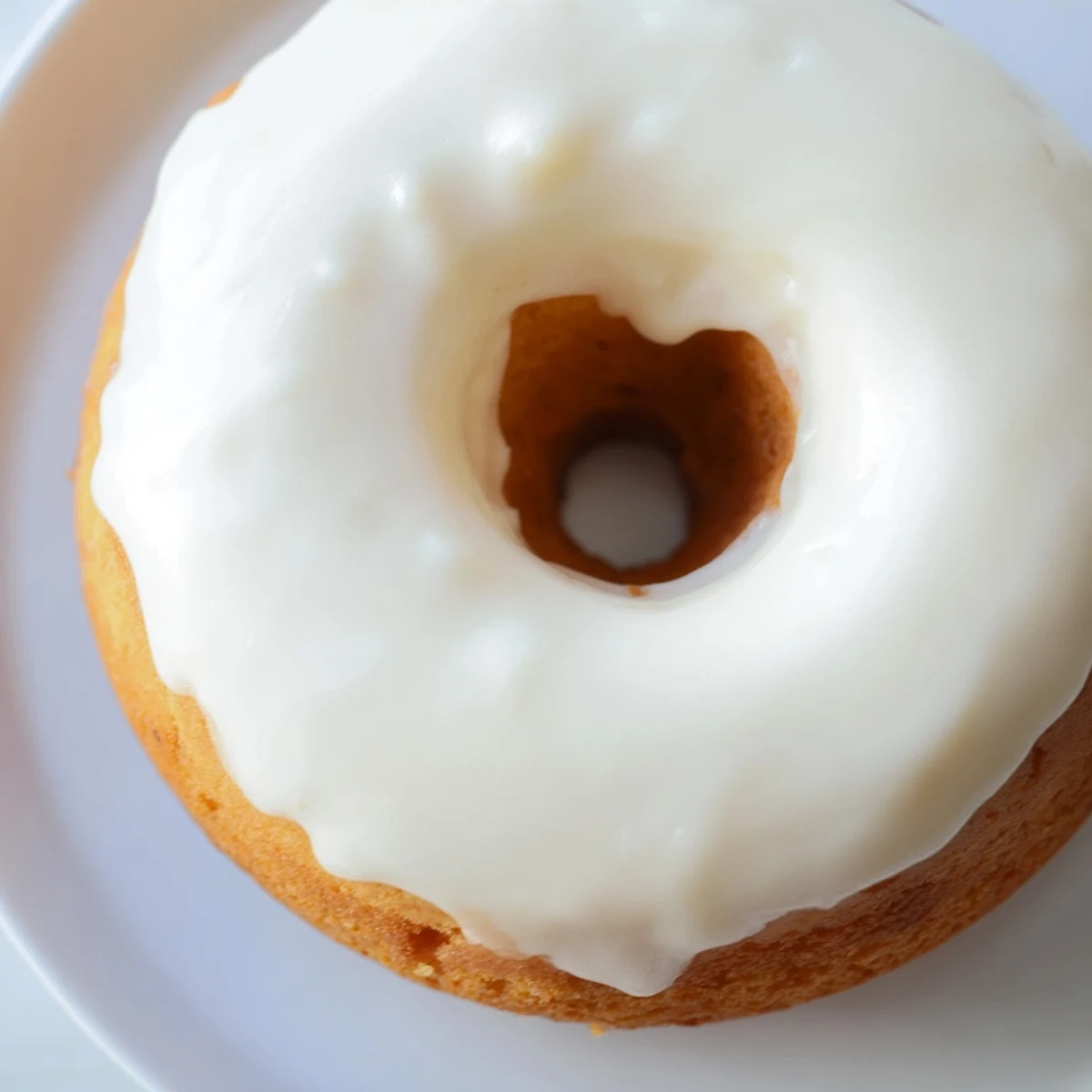 Close up of moist Greek yogurt cake donut with cinnamon speckled glaze dripping