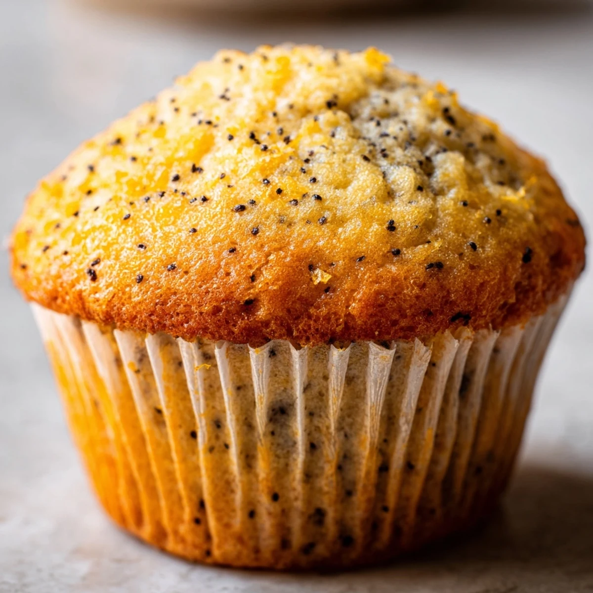 Golden lemon poppy seed muffins with domed tops sit in a rustic muffin tin ready for serving