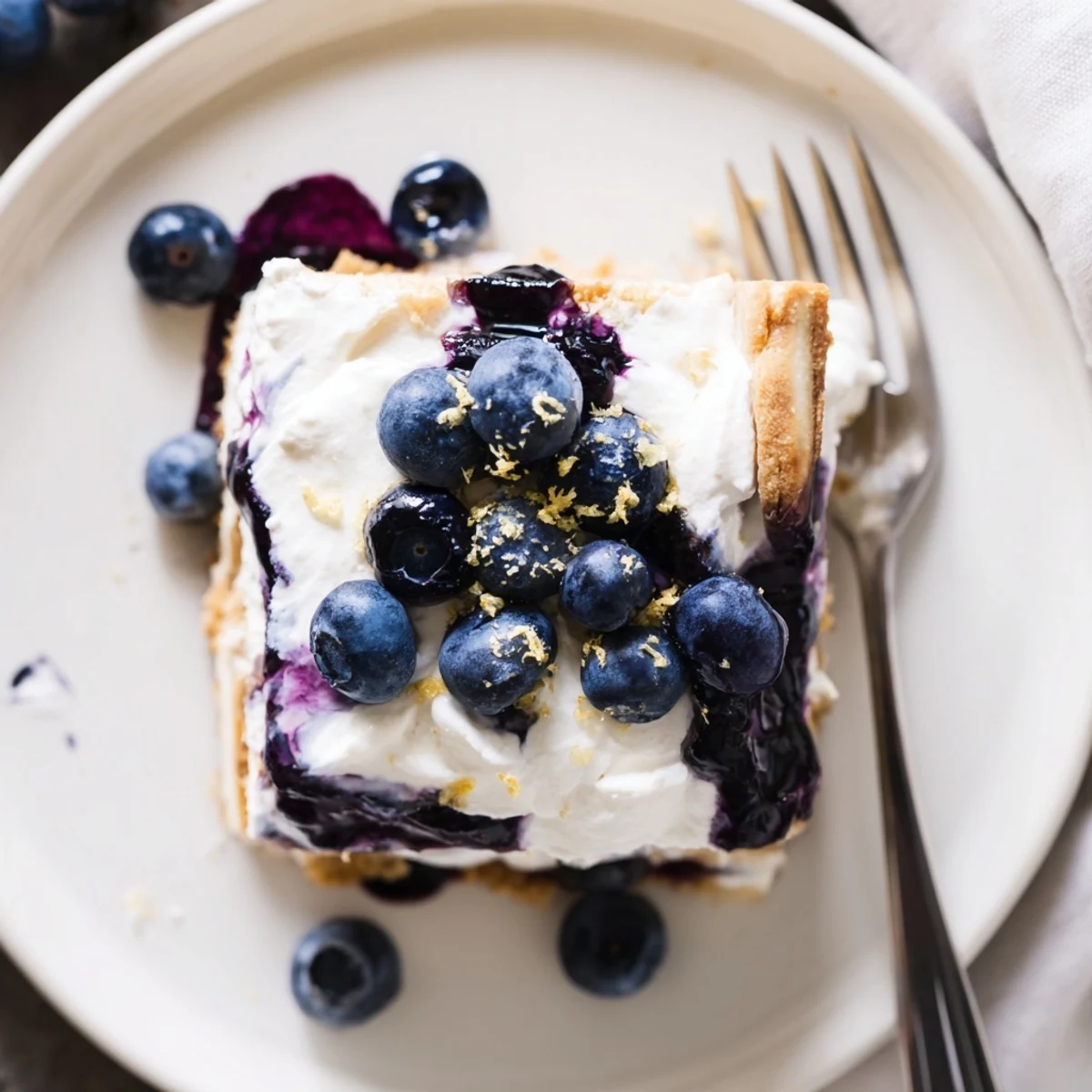 No-bake lemon blueberry lasagna recipe sliced in a glass dish topped with whipped cream