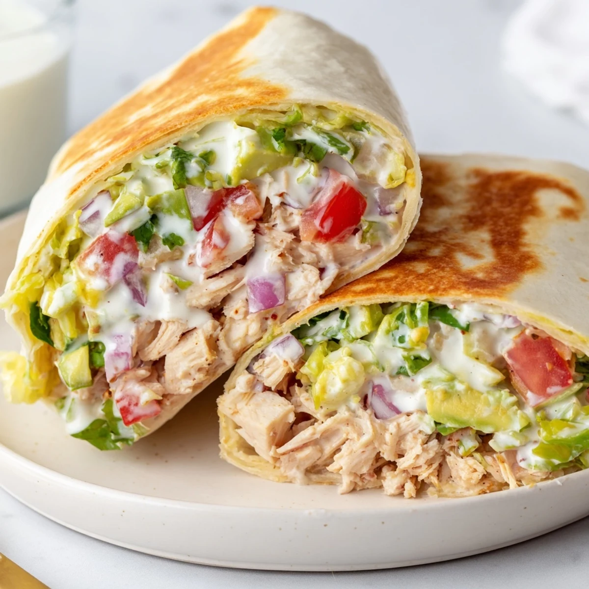 Chicken Avocado Ranch Burritos halved on plate, crisp skillet-seared exterior and cilantro