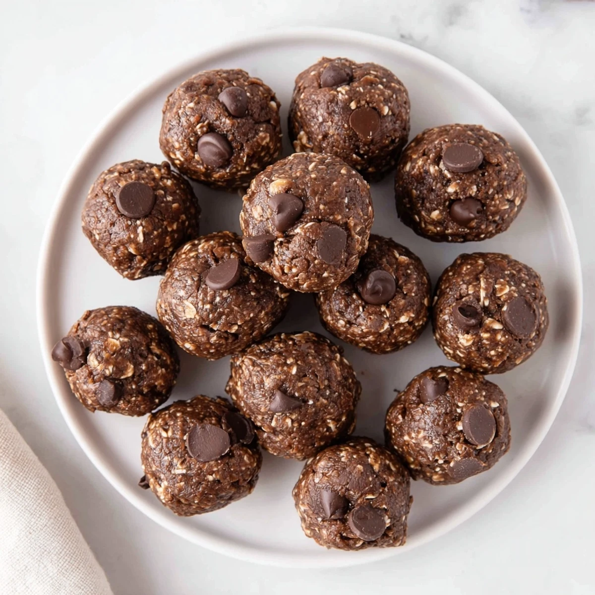 Hand rolled Brownie Protein Bites on tray, chilled for firm, biteable texture