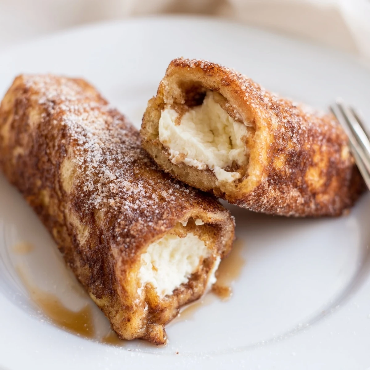 Cinnamon Roll French Toast Roll Ups frying golden in skillet, cream cheese center