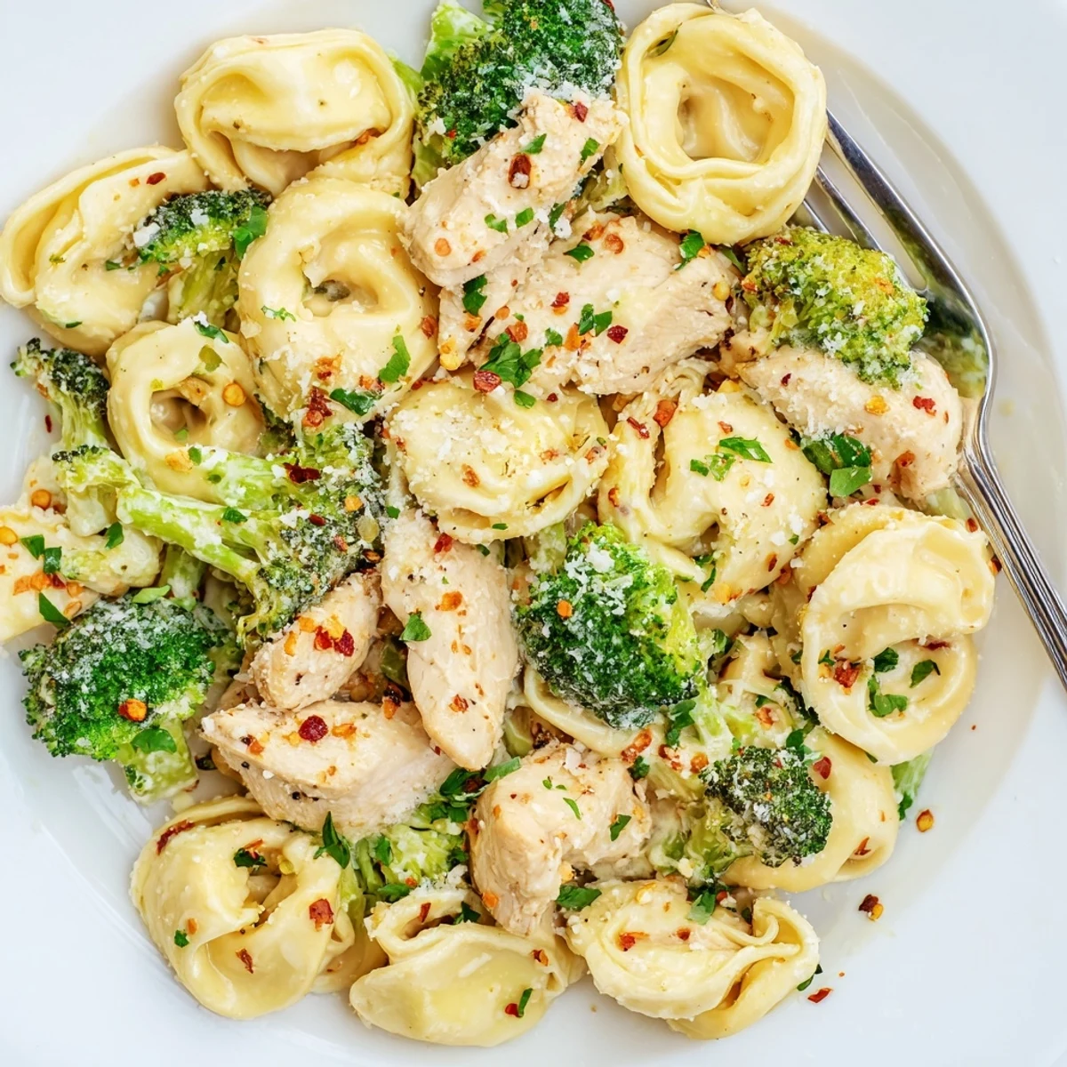Creamy Garlic Parmesan Tortellini Chicken Broccoli Recipe steaming, garnished with parsley and cracked pepper.