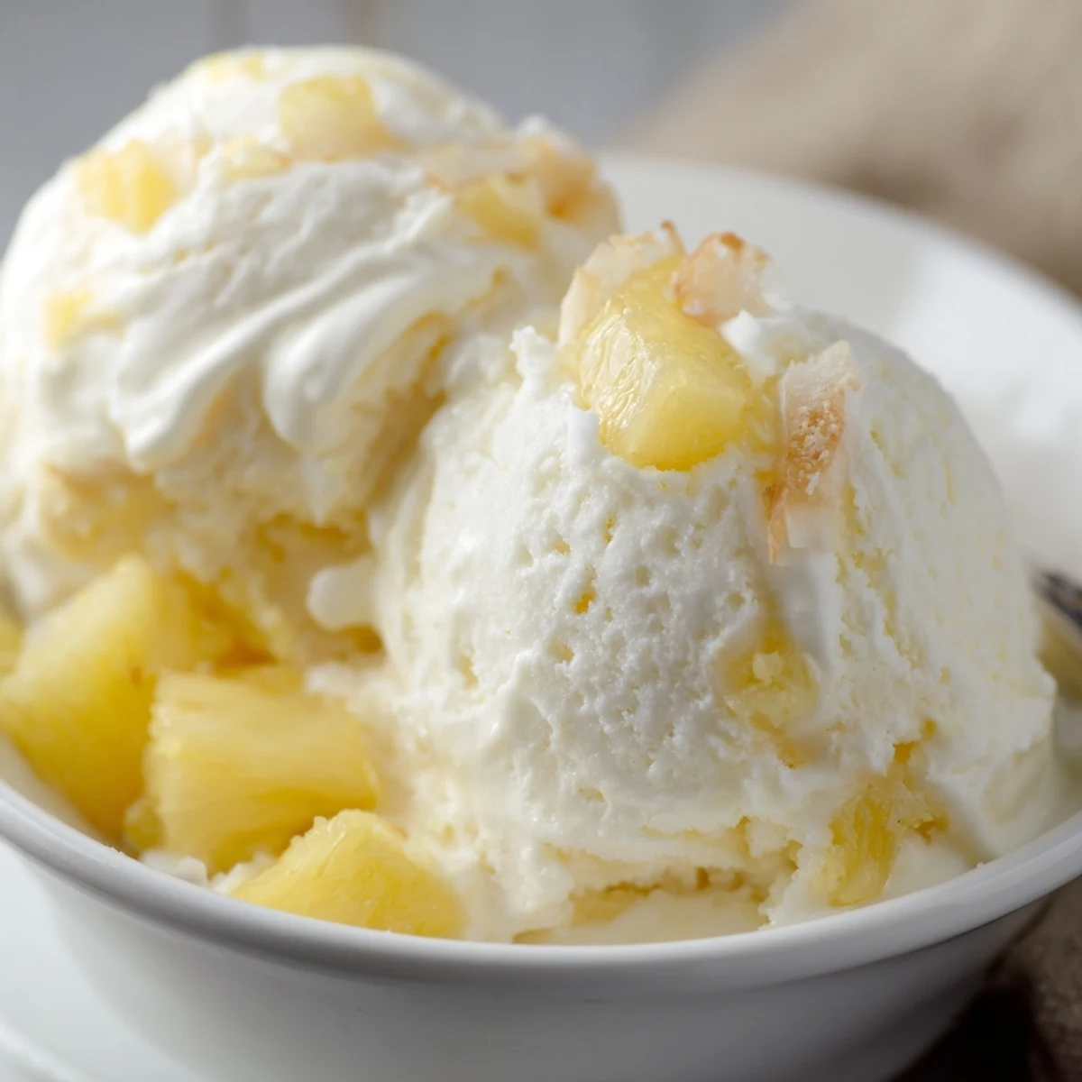 Scoops of Creamy Pineapple Ice Cream melting slightly, bright tropical aroma