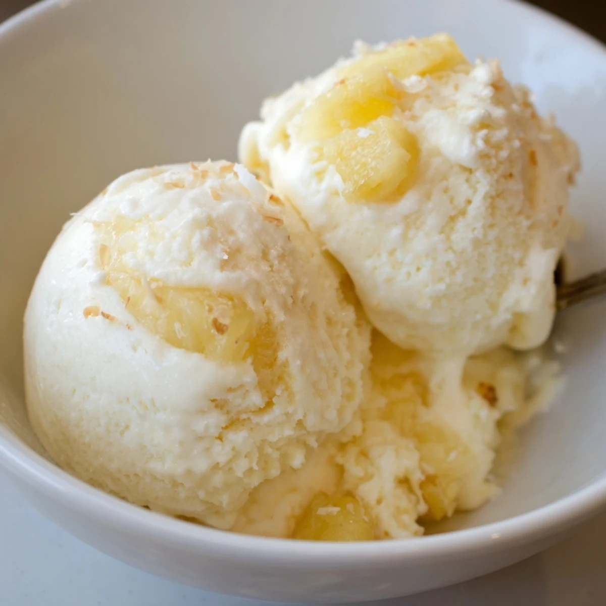 Creamy Pineapple Ice Cream served in a bowl garnished with toasted coconut