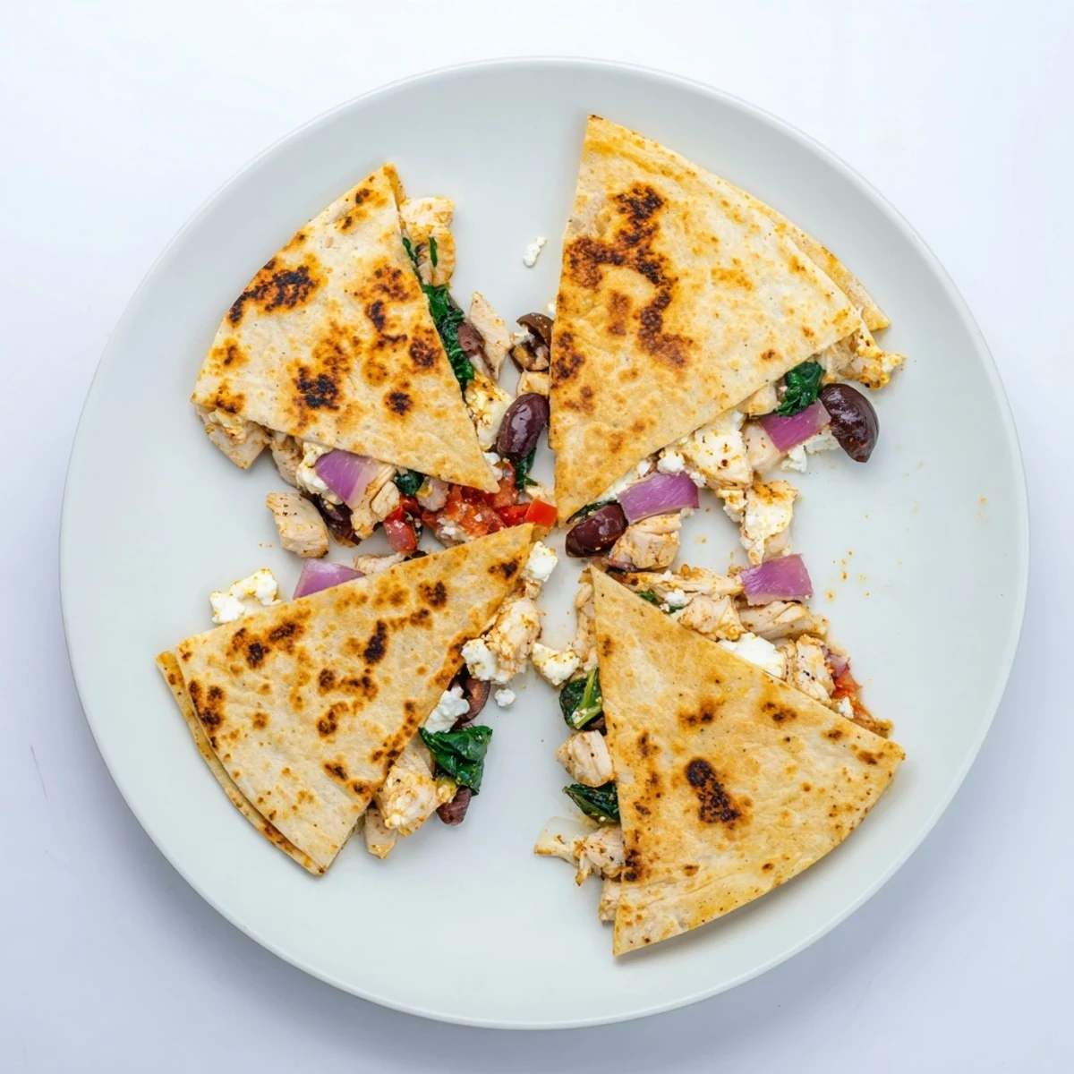 Crispy Greek chicken quesadilla with melted mozzarella and feta cheese on a white plate