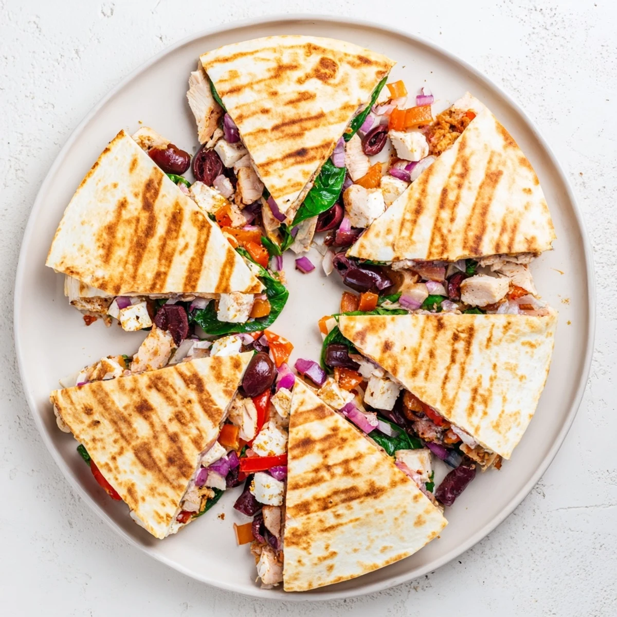 Slice of warm Greek chicken quesadilla showing melty cheese layers and Mediterranean vegetables