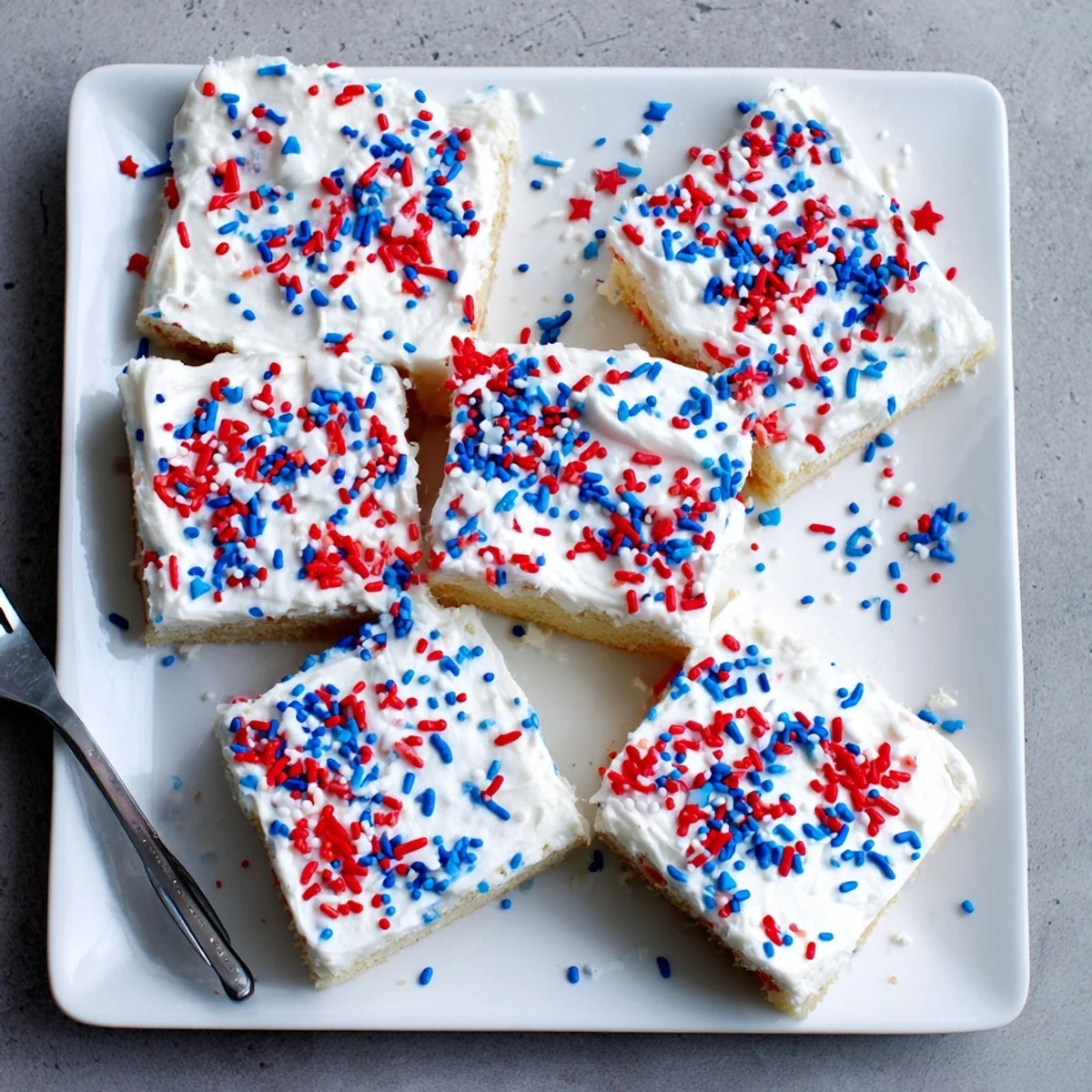 Baked patriotic 4th of July sugar cookie bars spread with vanilla frosting and decorated for Independence Day