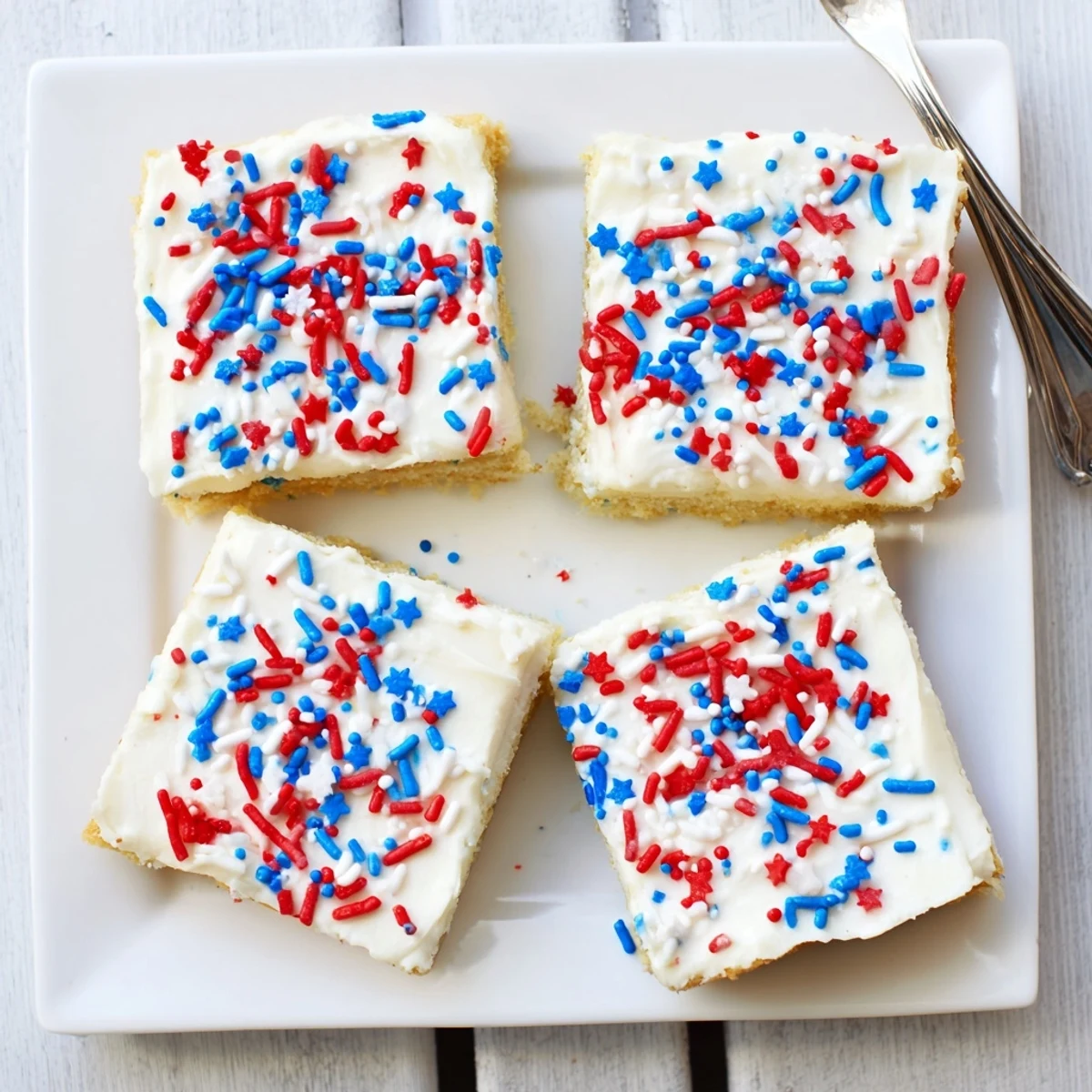 Golden sugar cookie bars for 4th of July celebrations layered with buttercream frosting and colorful sprinkles on top