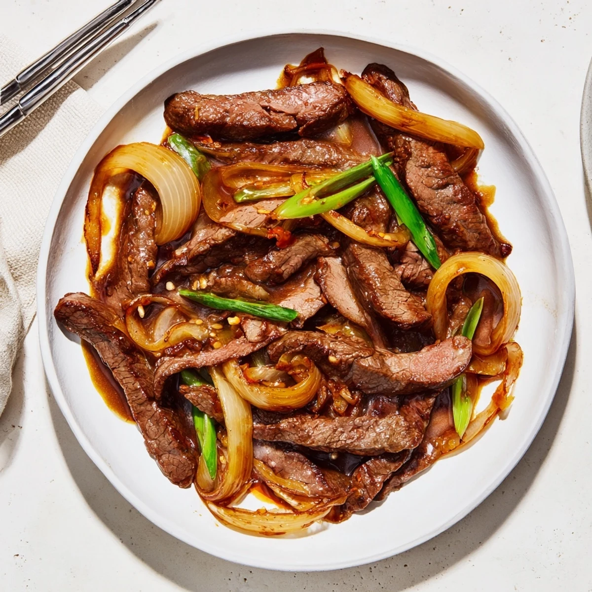 Homemade crispy beef and onion stir fry garnished with fresh green spring onions
