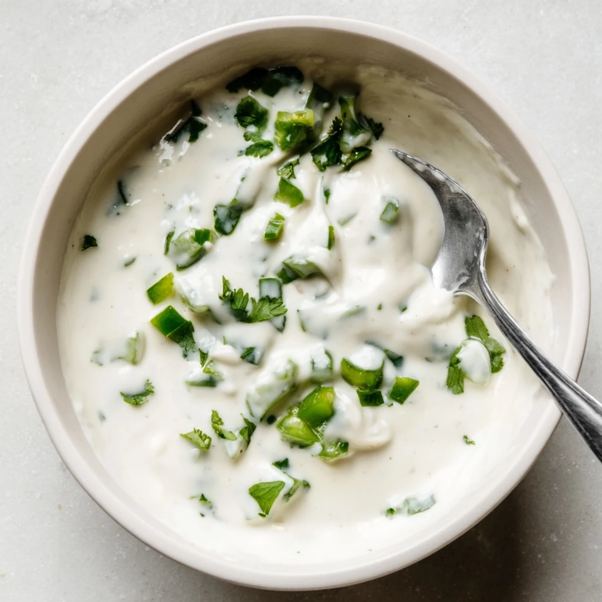 Thick white Mexican sauce spooned onto grilled chicken with lime wedge on side