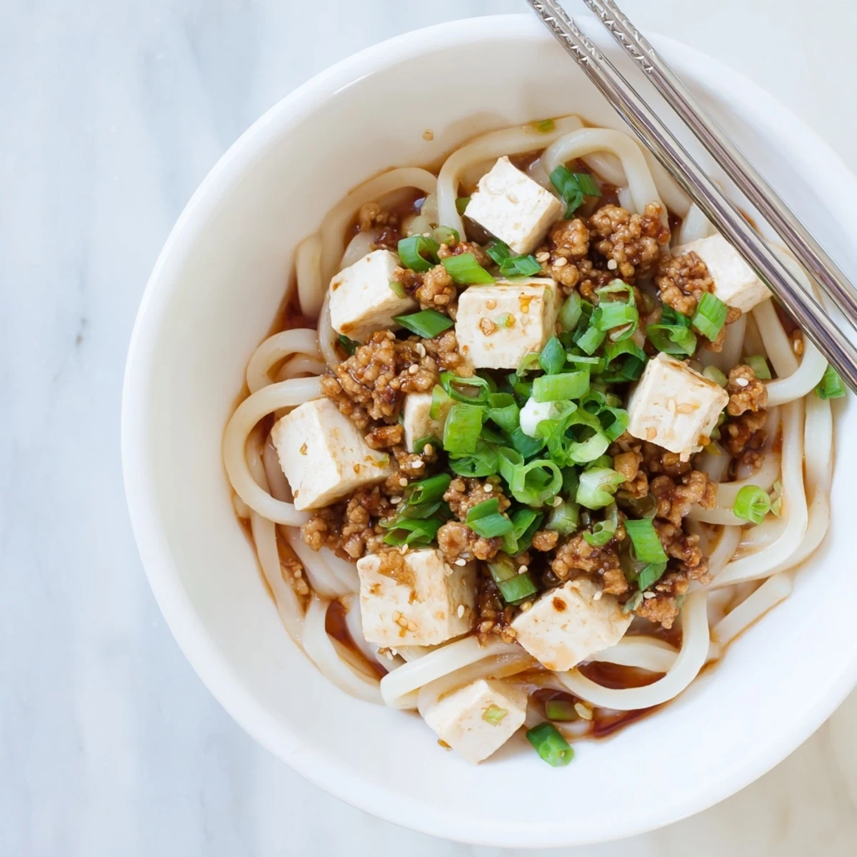 Steamy bowl of Mapo Tofu Udon with chewy noodles and spicy red sauce