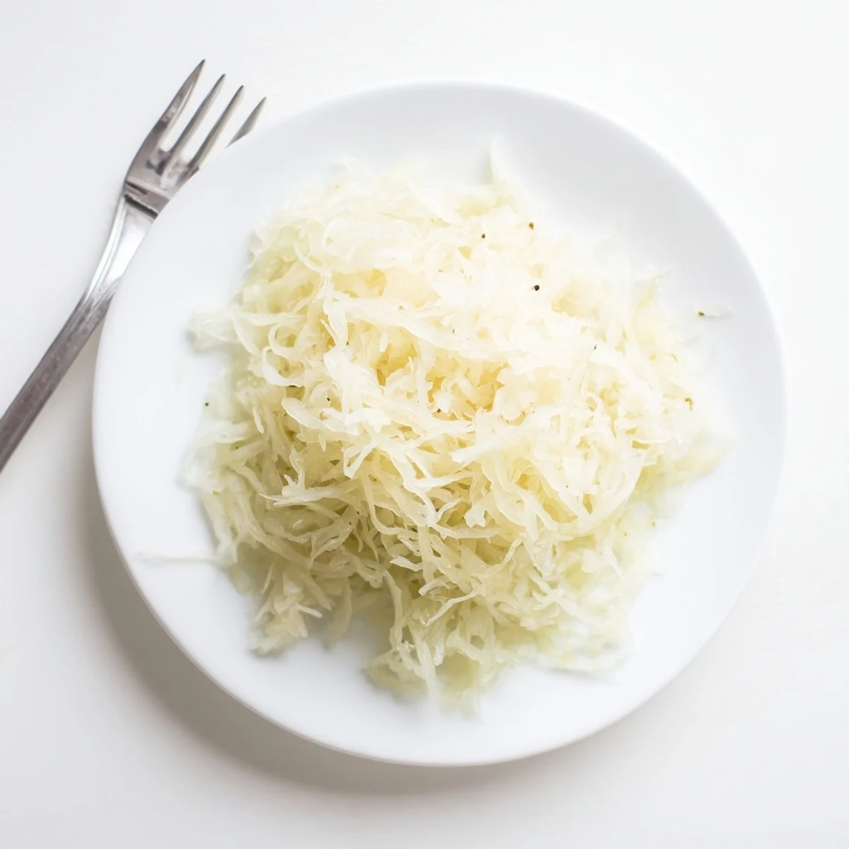 Classic German sauerkraut served in rustic bowl alongside traditional sausage and potatoes