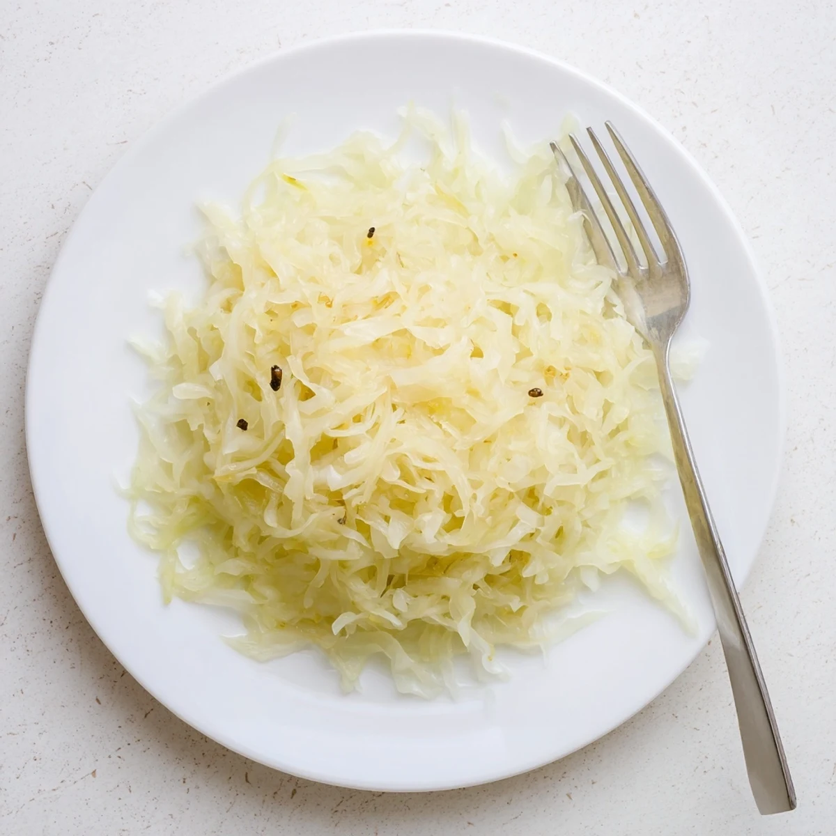 Fresh sauerkraut recipe fermenting in crock with naturally brined white cabbage strands