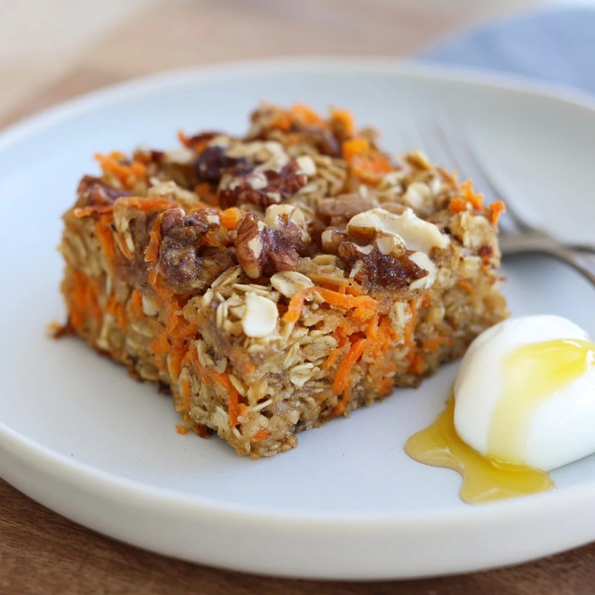Hearty Carrot Cake Baked Oatmeal squares topped with creamy yogurt and maple syrup