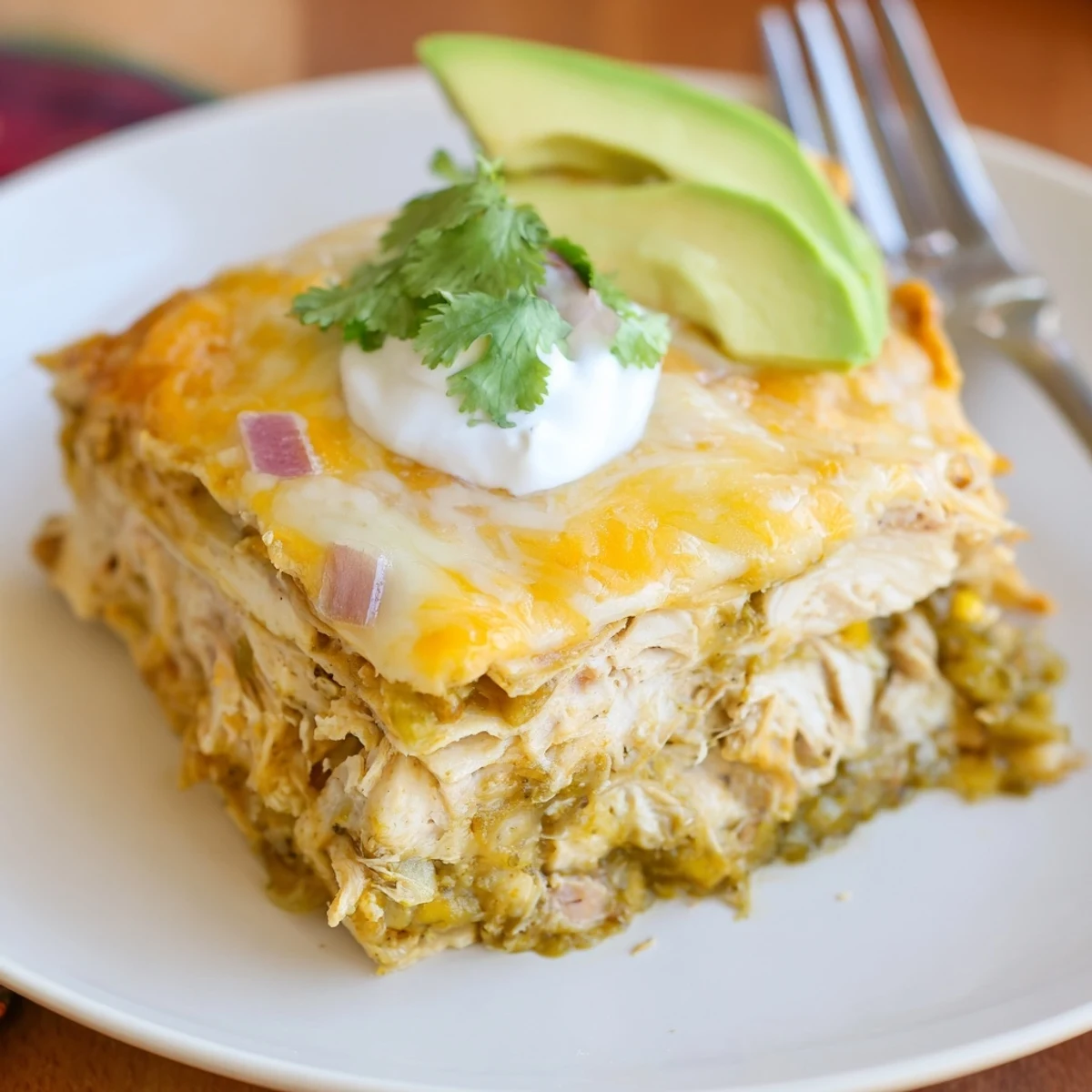 Salsa Verde Chicken Casserole bubbling golden cheese, cilantro and lime garnish.
